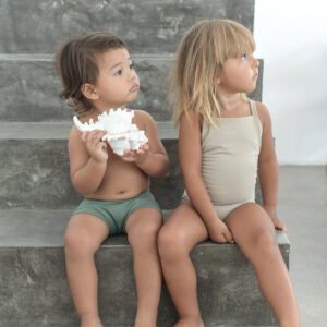 Two children, Mara and Sand, sitting on a set of stairs wearing matching Mara One-Piece outfits.