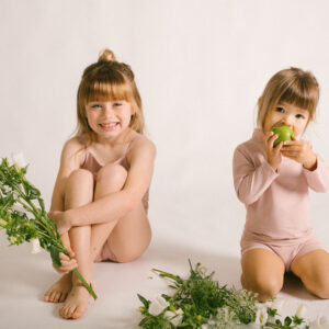 Two little girls sitting on a white background with Lumi Short Swim Nappy.