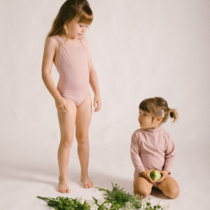 Two little girls standing next to each other in a pink Mara One-Piece.