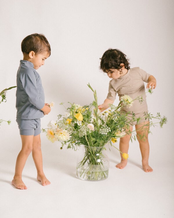 Two toddlers playing with Lumi Short Swim Nappy in a vase.