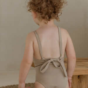 The back of a child wearing the Essentials Range - Mara One-Piece - Sand Colour swimsuit.