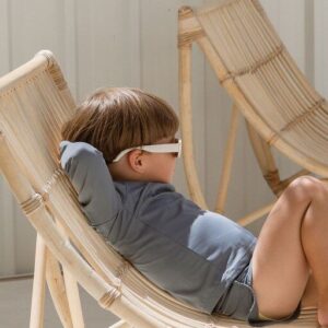 Child relaxing in a deck chair wearing Ada Rash Shirt - Mineral Colour sunglasses.