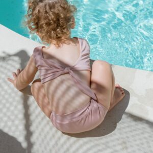 A little girl in the Essentials Range - Arla Bikini - Rose Colour sitting on the edge of a pool.