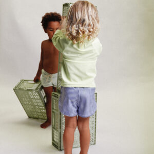 Two children standing in front of a Playtime Collection - Mesa Trunks - Berry Stripe.