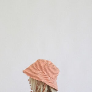 A little girl wearing a Playtime Collection - Lumi Brief Swim Nappy - Mandarin hat.