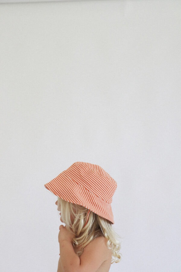 A little girl wearing a Playtime Collection - Lumi Brief Swim Nappy - Mandarin hat.