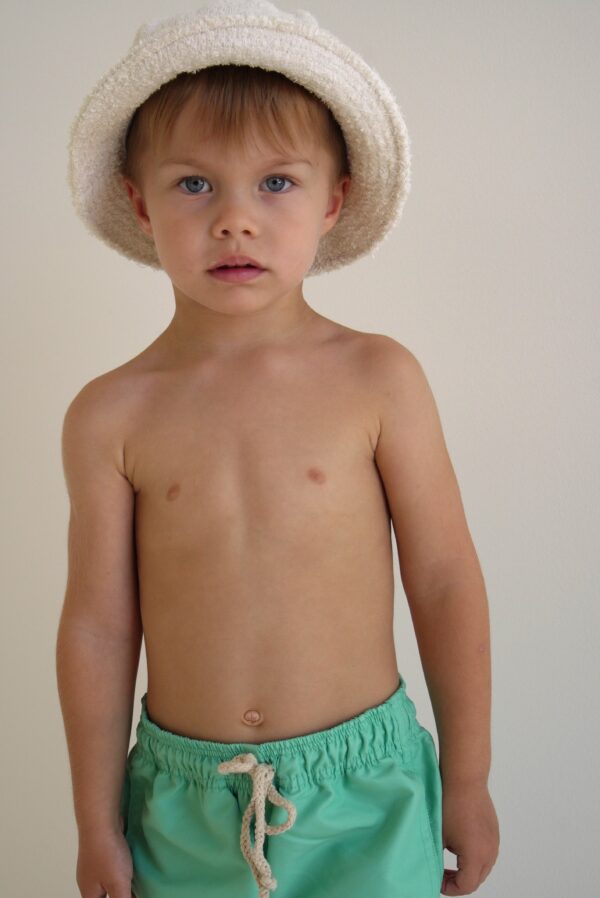 A young boy wearing a white hat and Sorbet Summer - Sea Shorts.