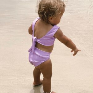 A baby girl in a Sorbet Summer - Arla Bikini - Grape Colour standing on the beach.