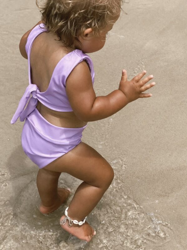 A little girl in a Sorbet Summer - Arla Bikini - Grape Colour playing in the sand.