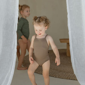 Essentials Range - Mara One-Piece - Tort Colour, a little girl, wearing a tan one-piece swimsuit.