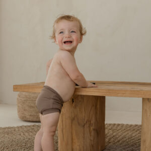 A baby standing on top of a Essentials Range - Lumi Short Swim Nappy - Tort Colour.