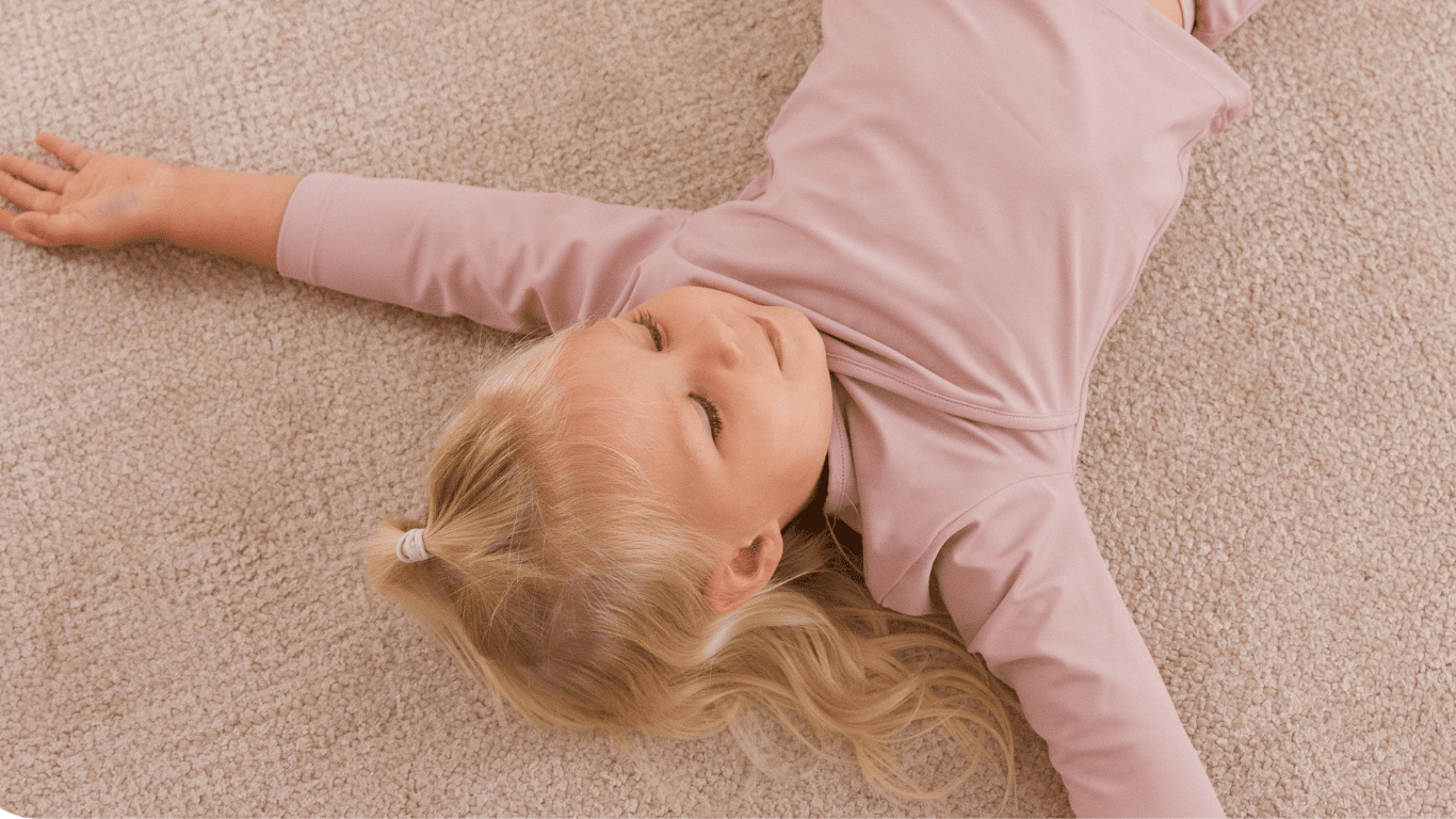 A little girl enjoying sustainable swimwear on a carpet.