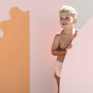 Child standing beside Mesa Trunks - Marigold Stripe panels.