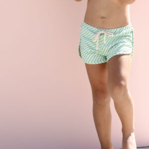 Child in Mesa Trunks - Fern Stripe standing against a pink background.