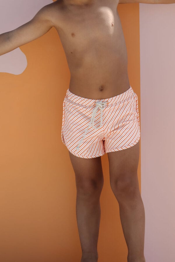 A person wearing Mesa Trunks - Marigold Stripe standing against a dual-toned background.