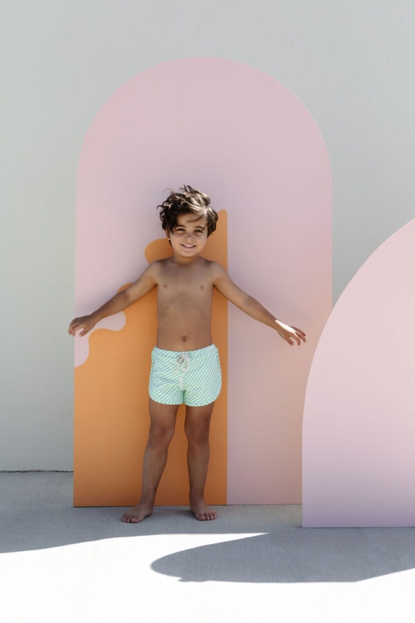 A child standing in front of a Mesa Trunks - Fern Stripe arch-shaped backdrop.