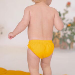 A baby in a Retro Wave By Ina - Lumi Brief Swim Nappy standing on a rug.