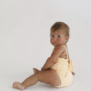 A baby in a Retro Wave By Ina - Mara One-Piece swimsuit sitting on the floor.