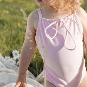 A little girl in a WS - Golden Meadows Collection - Aurelia One-Piece standing in a field.