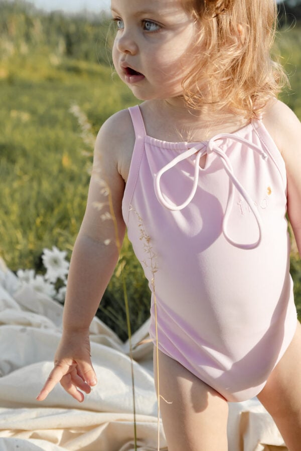 A little girl in a WS - Golden Meadows Collection - Aurelia One-Piece standing in a field.