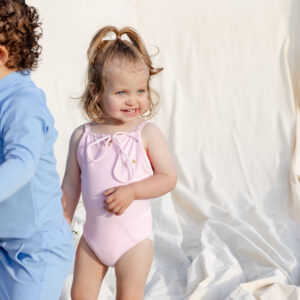 Two children in WS - Golden Meadows Collection - Aurelia One-Piece swimsuits playing on a white sheet.