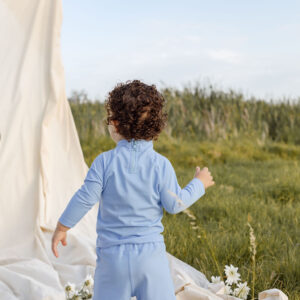 A baby is standing in a field next to WS - Golden Meadows Collection - Amias Trunks.