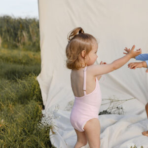 Two children playing on a WS - Golden Meadows Collection - Aurelia One-Piece in a field.