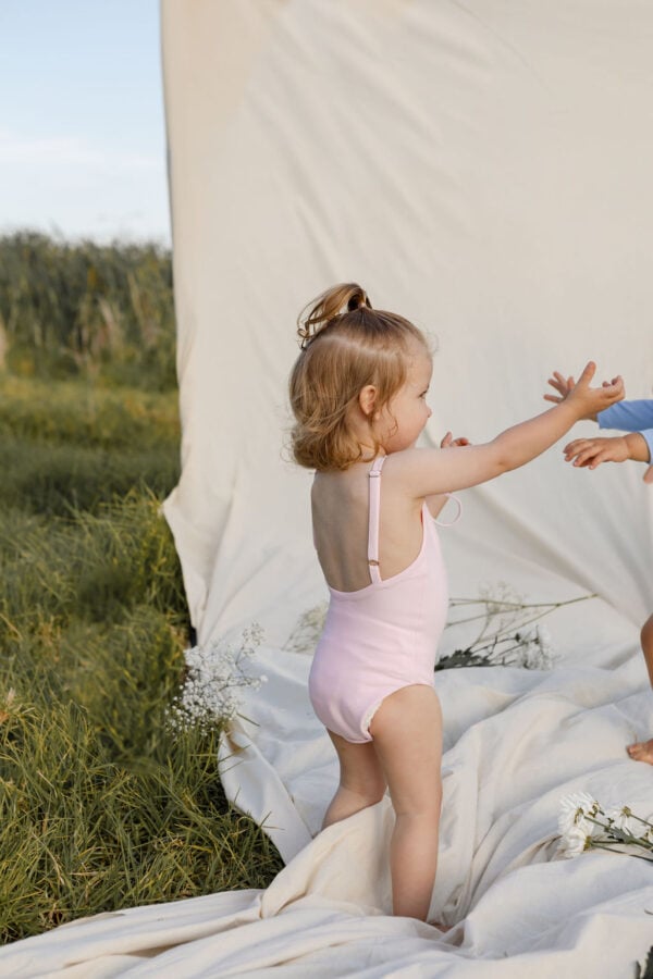 Two children playing on a WS - Golden Meadows Collection - Aurelia One-Piece in a field.