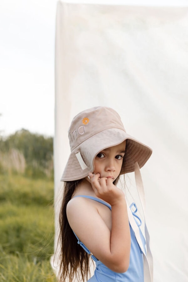 A little girl wearing the WS - Golden Meadows Collection - Golden Sun Bucket Hat in a field.