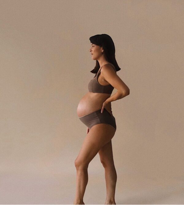 A pregnant woman in The Bay Swim Brief - Tort Colour standing in front of a white background.