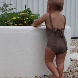 A baby wearing a brown Essentials Range - Mara One-Piece - Tort Colour swimsuit.