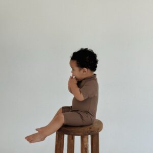 A baby sitting on a Zimmi Onesie - Tort.