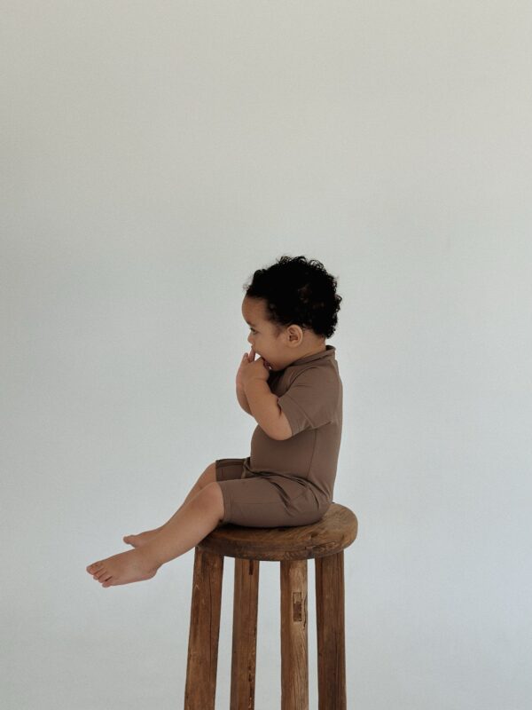 A baby sitting on a Zimmi Onesie - Tort.