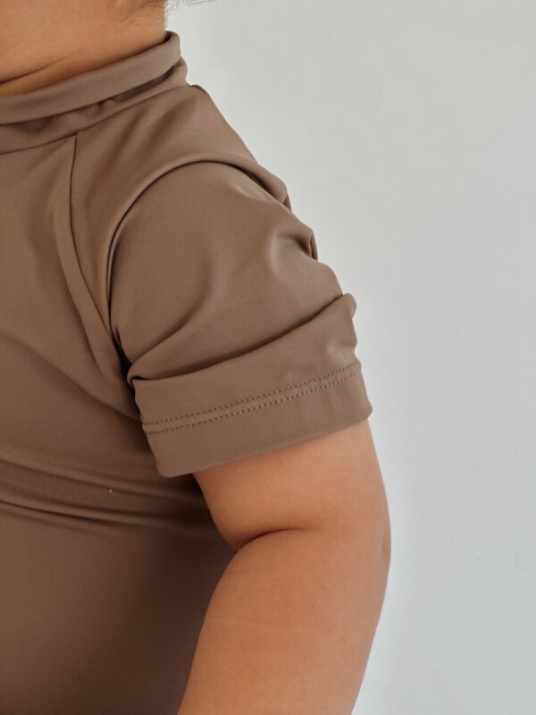 A baby wearing a brown Essentials Range - Zimmi Onesie - Tort shirt.